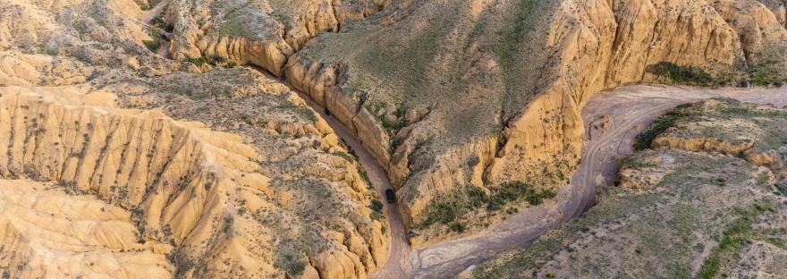 A overhead view of a canyon with a white car in the center.