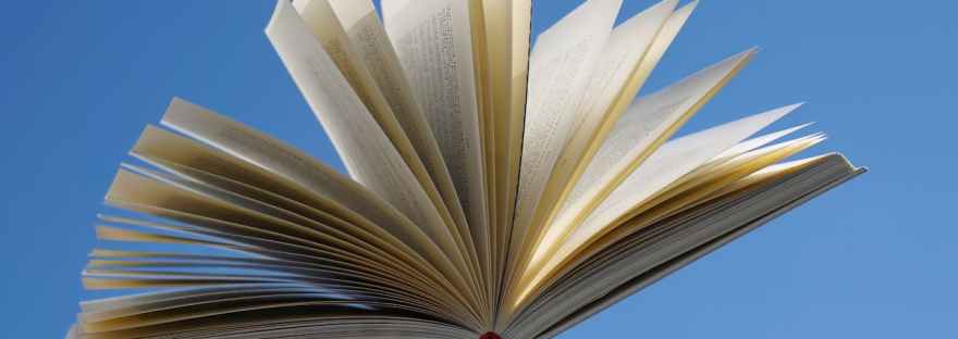 A book thrown in the air against a bright blue sky