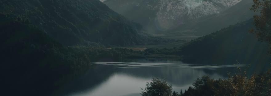 Grey mountains against a grey sky with a grey river winding through them.
